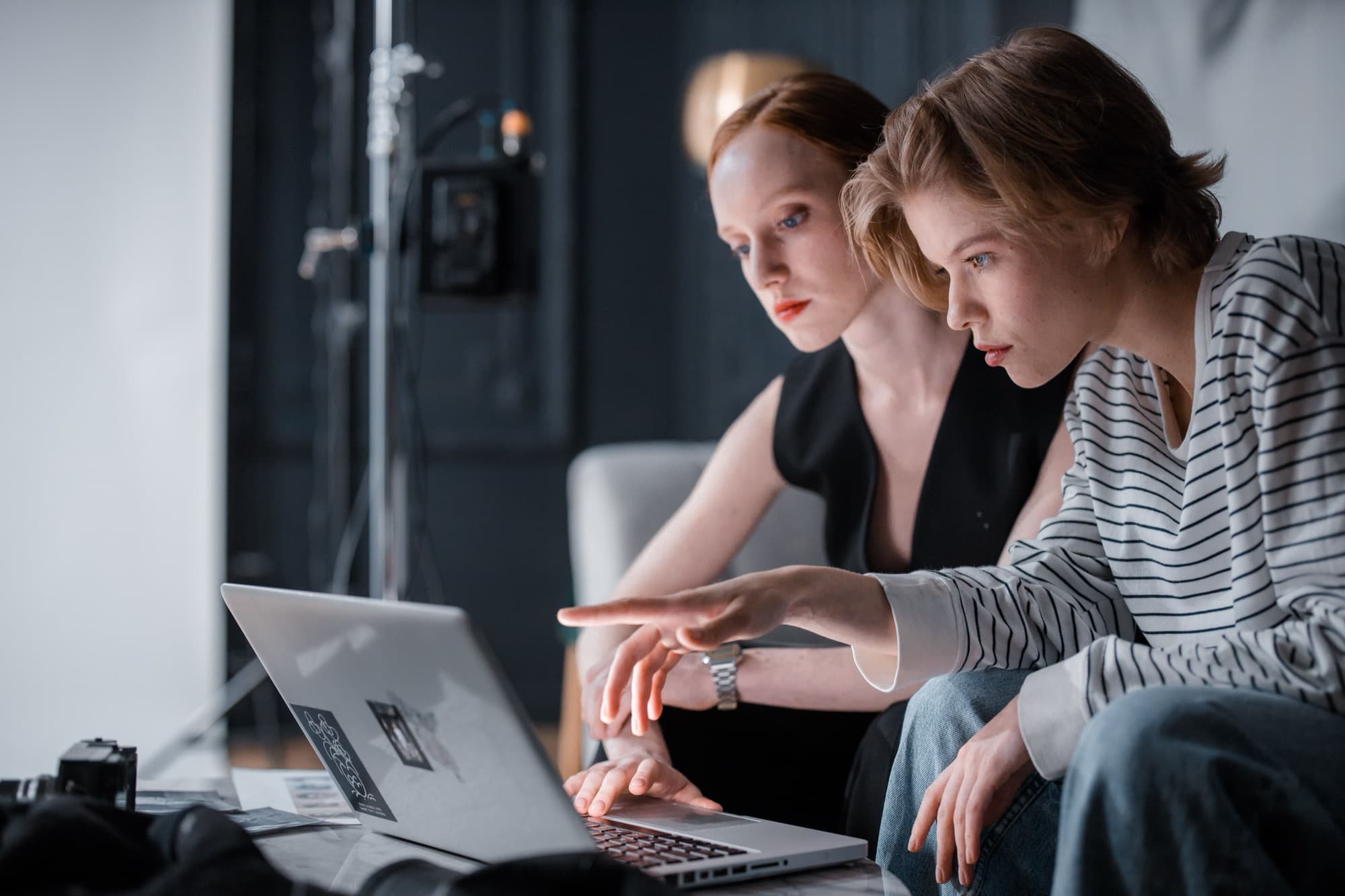 Two designers reviewing printed photographs on a table in a studio